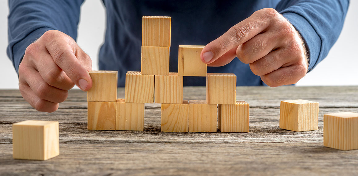 Man Assembling Wooden Cubes on Table