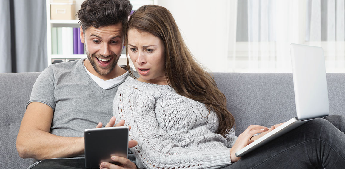 Junges Pärchen schaut erstaunt auf ein Tablet Computer