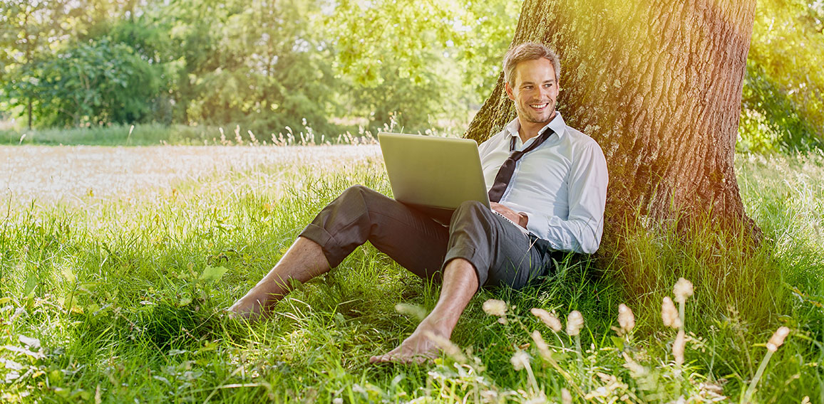 handsome grey hair man using a laptop, barefoot in the grass