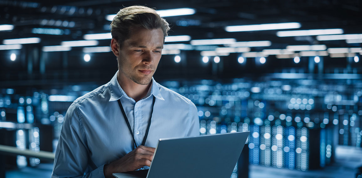 Handsome Smiling IT Specialist Using Laptop Computer in Data Cen