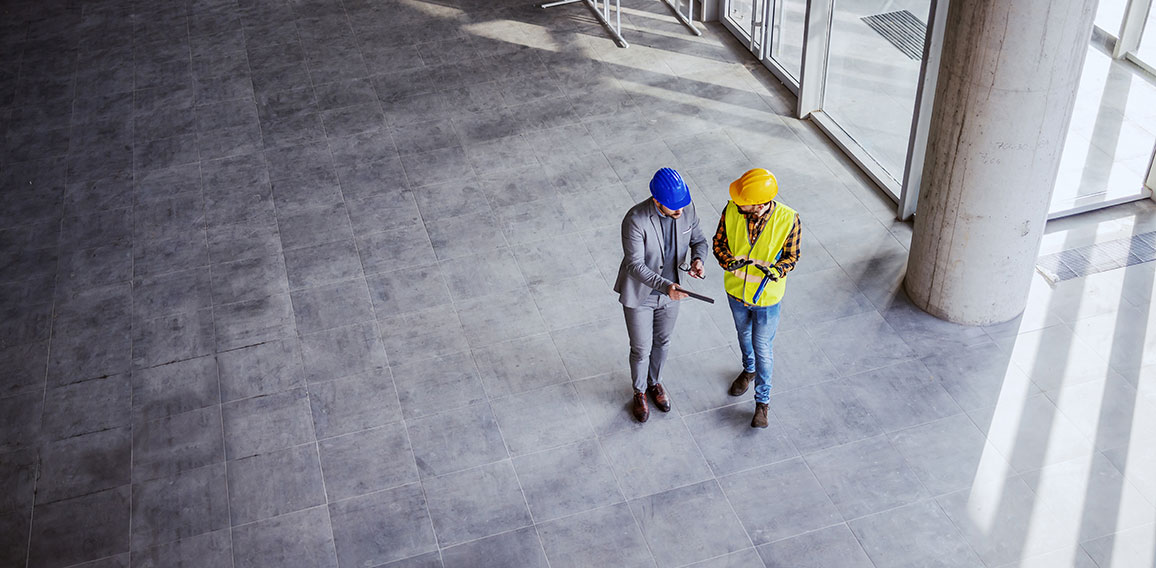 Top view of architect holding tablet and talking with constructi