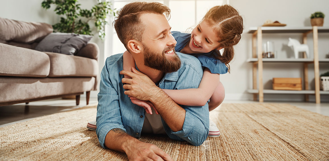 Cheerful father and daughter having fun and hugging in living room