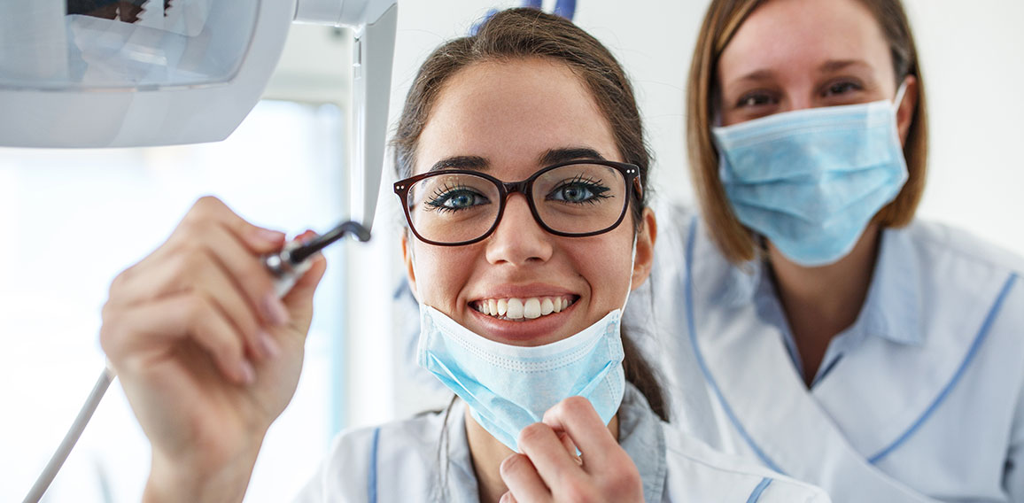 Two female dentist in dental office examining patient teeth.Came