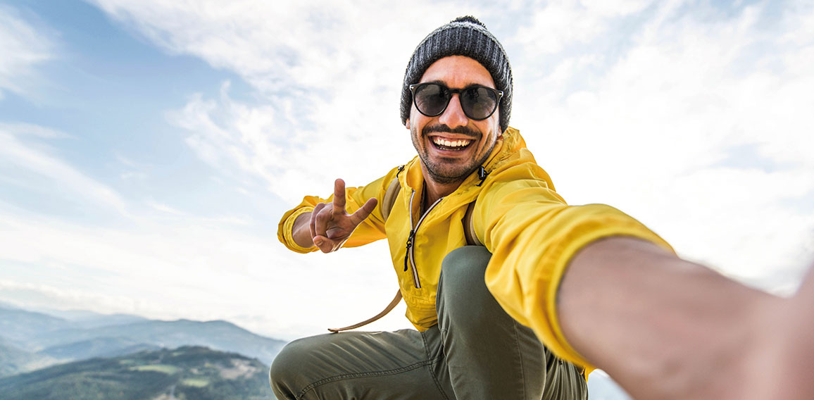 Young hiker man taking selfie portrait on the top of mountain -