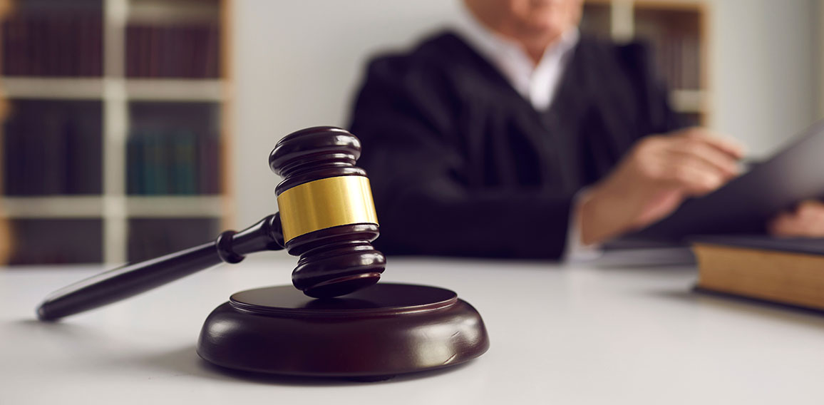 Close-up of wooden gavel placed on sound block on judge's table during court hearing