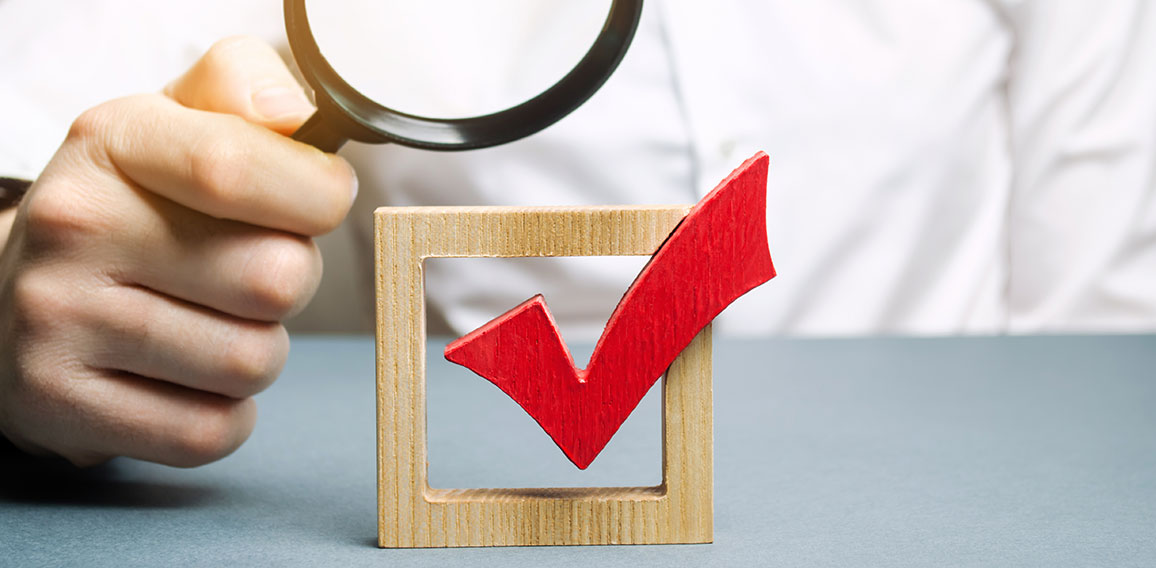 A man examines a red check mark through a magnifying glass. Assessing the transparency of the legitimacy of an election or referendum. Illegal Anex, falsifications and violations. Democracy.