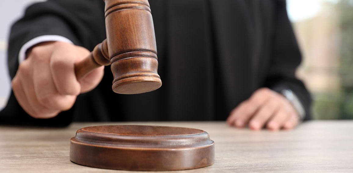 Judge with gavel at wooden table indoors, closeup. Criminal law