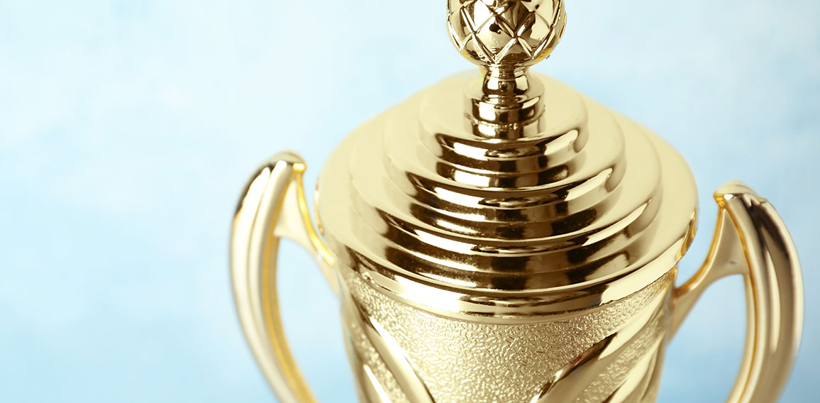 Shiny golden trophy cup on blue background, closeup