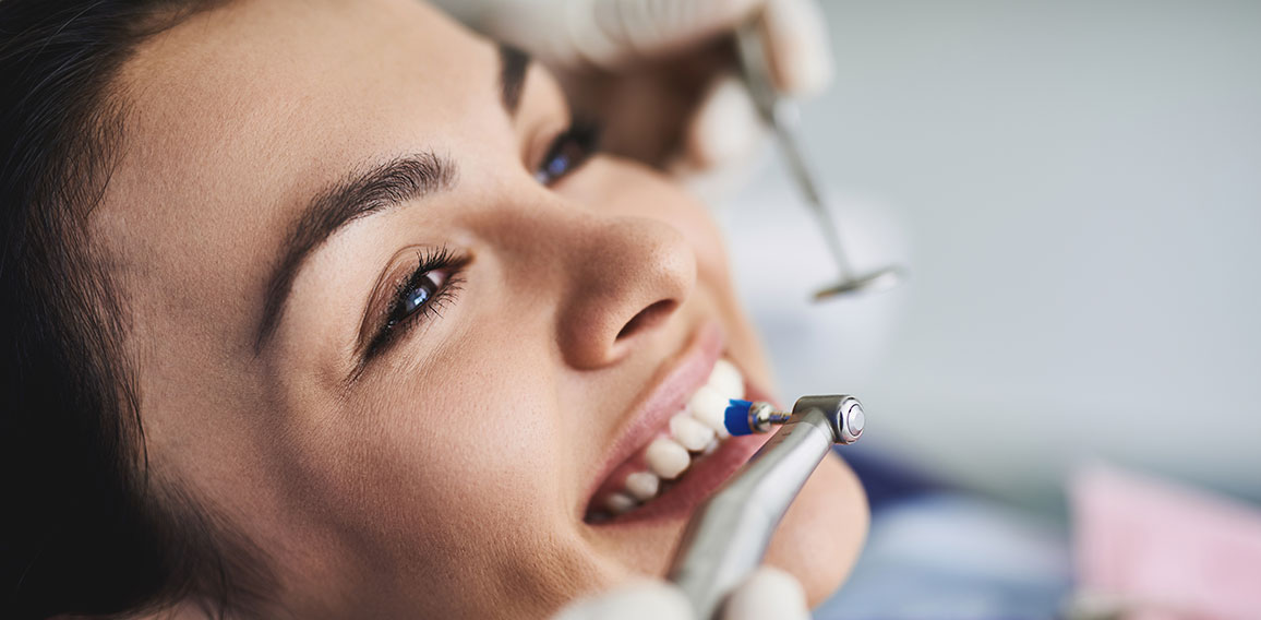 Charming young lady receiving teeth cleaning and polishing at clinic