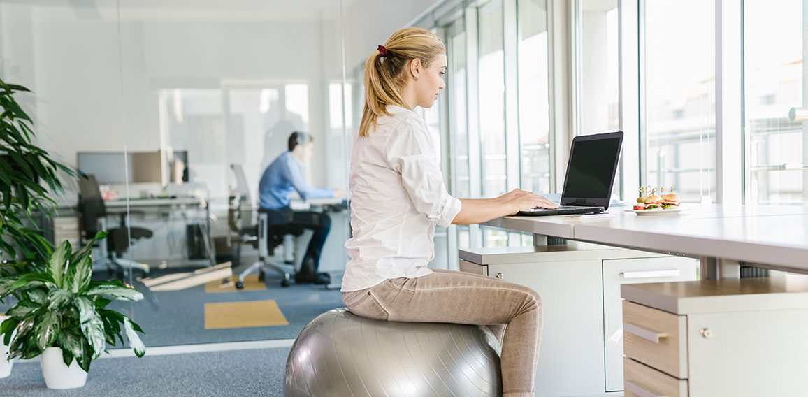 Business woman working on laptop in office while sitting on pila