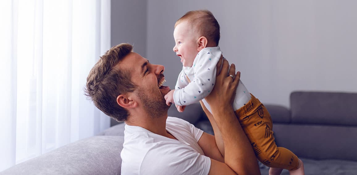 Playful handsome caucasian young dad lifting his loving 6 months