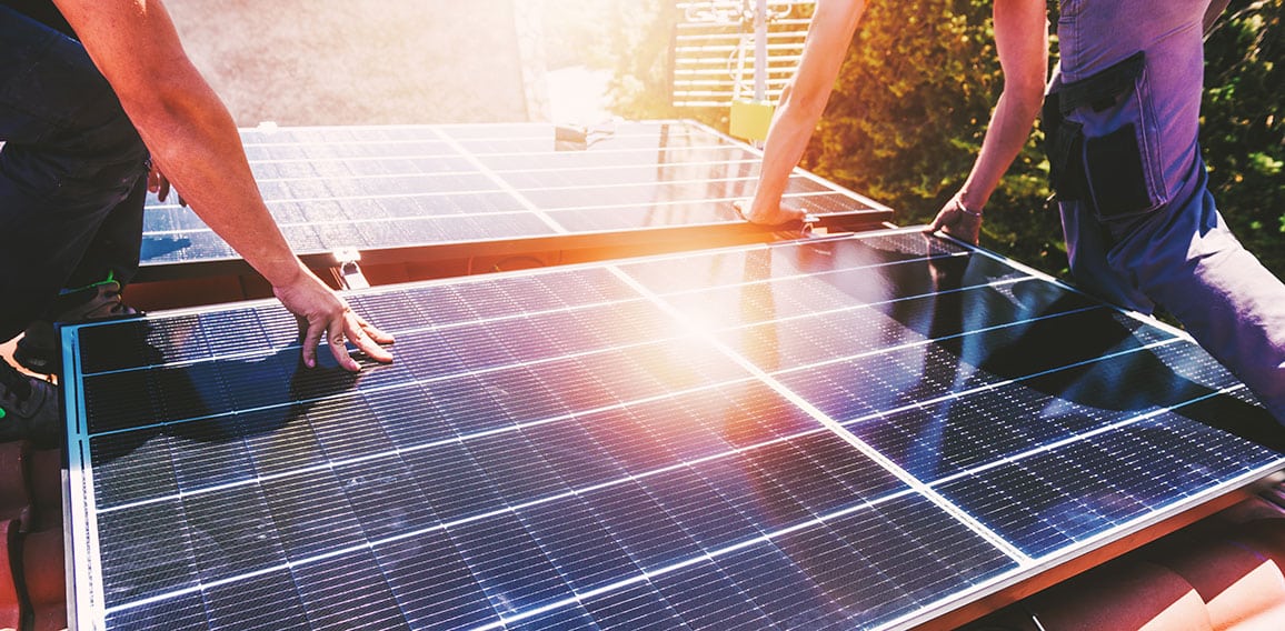 Workers assemble energy system with solar panel for electricity and hot water