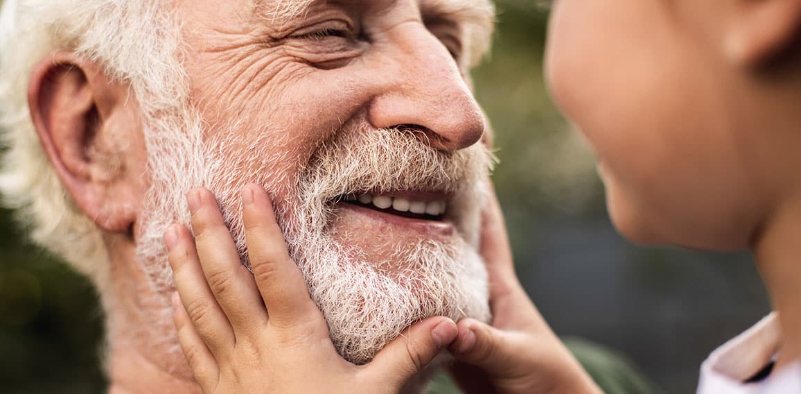 Old smiling man and his granddaughter looking each other