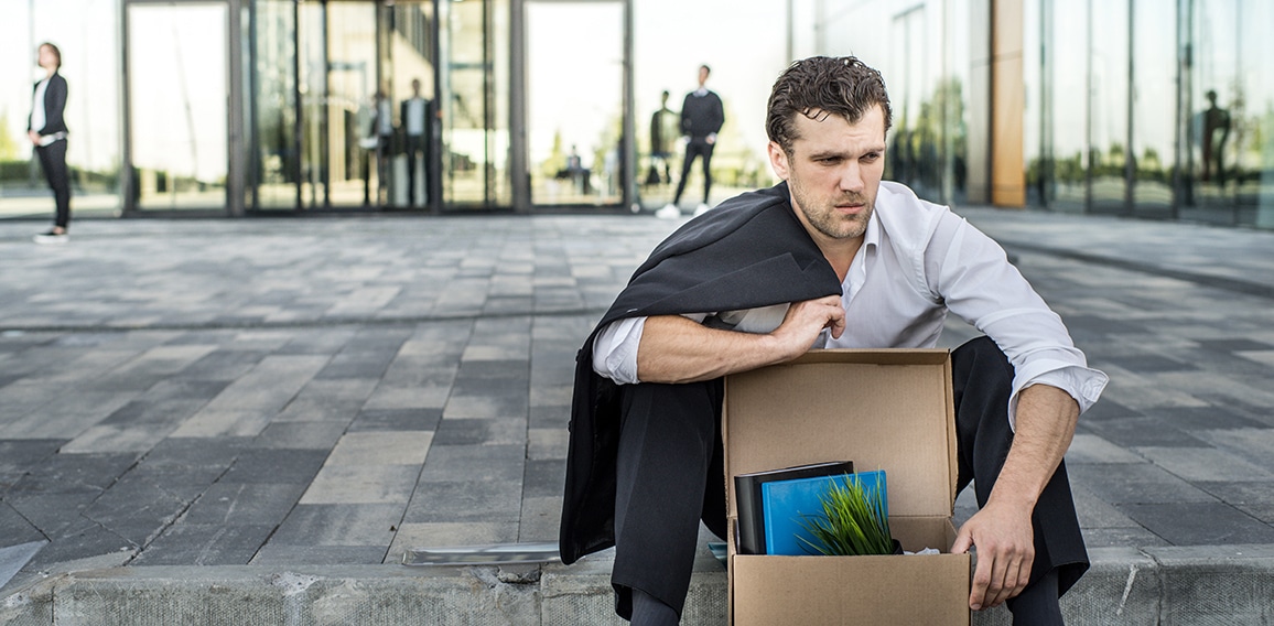 Fired businessman sitting on street