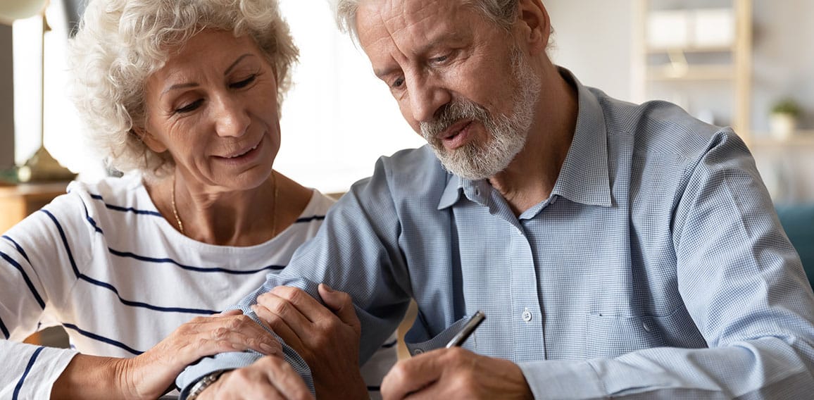 Happy senior couple signing legal documents, making purchasing deal