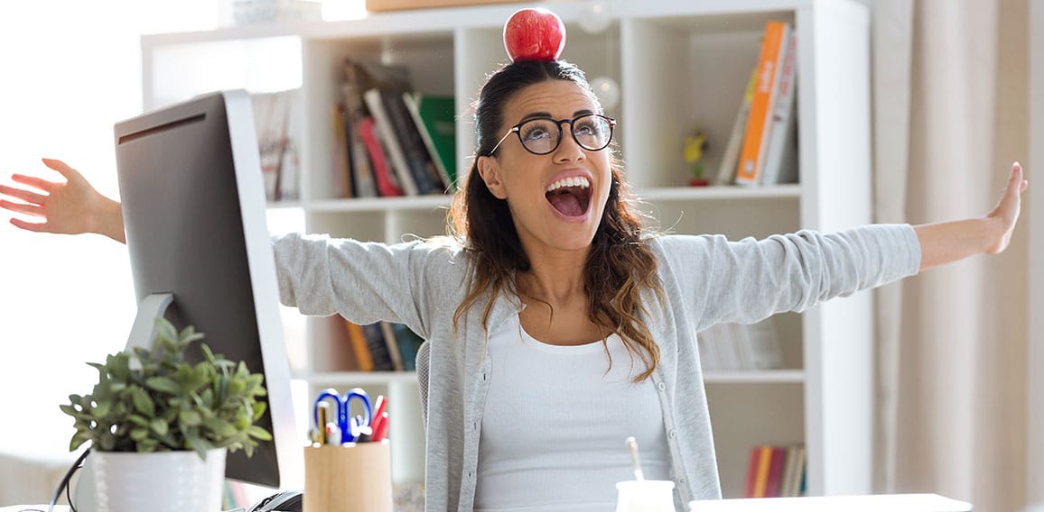 Happy young business woman having fun and holding red apple over