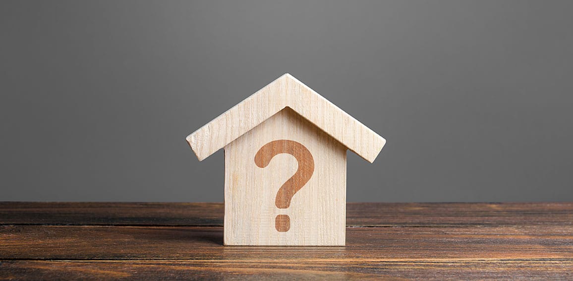 Question mark on a wooden house. Solving housing problems, deciding to buy or rent real estate. Search for options, the choice of accommodation between apartment and house. Cost estimate