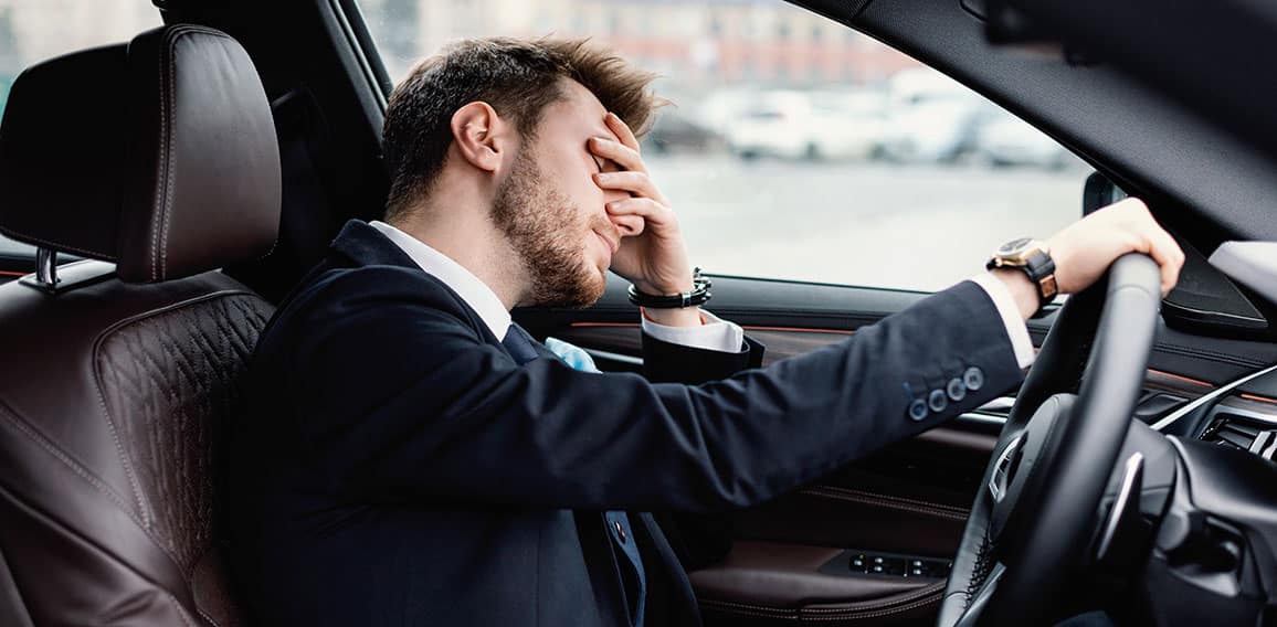 Sad young businessman driving alone in his new car