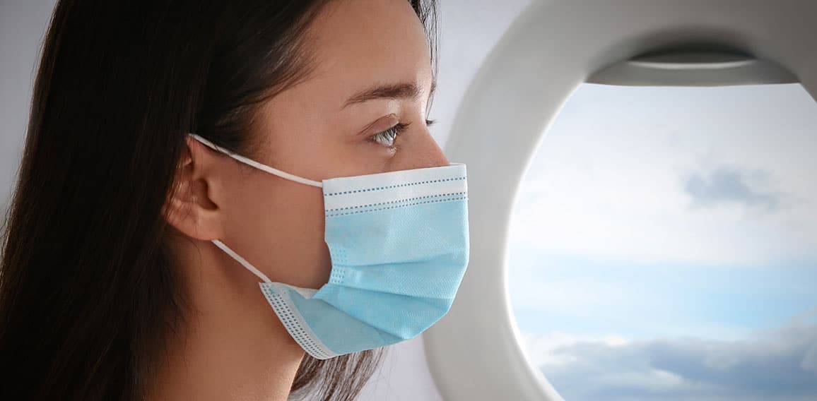 Traveling by airplane during coronavirus pandemic. Woman with fa