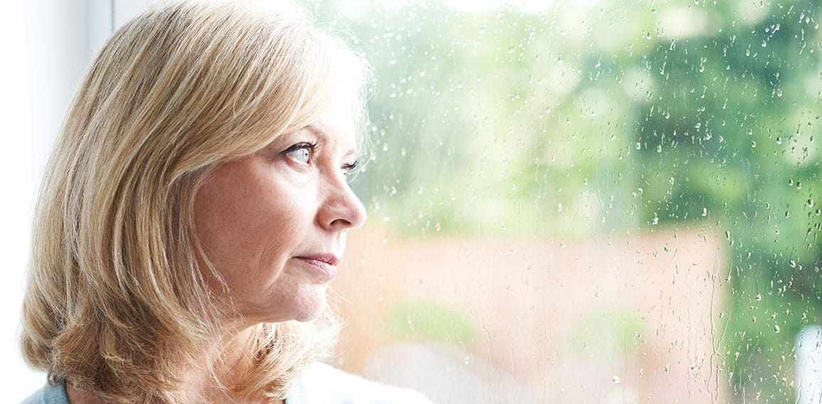 Sad Mature Woman Suffering From Agoraphobia Looking Out Of Windo