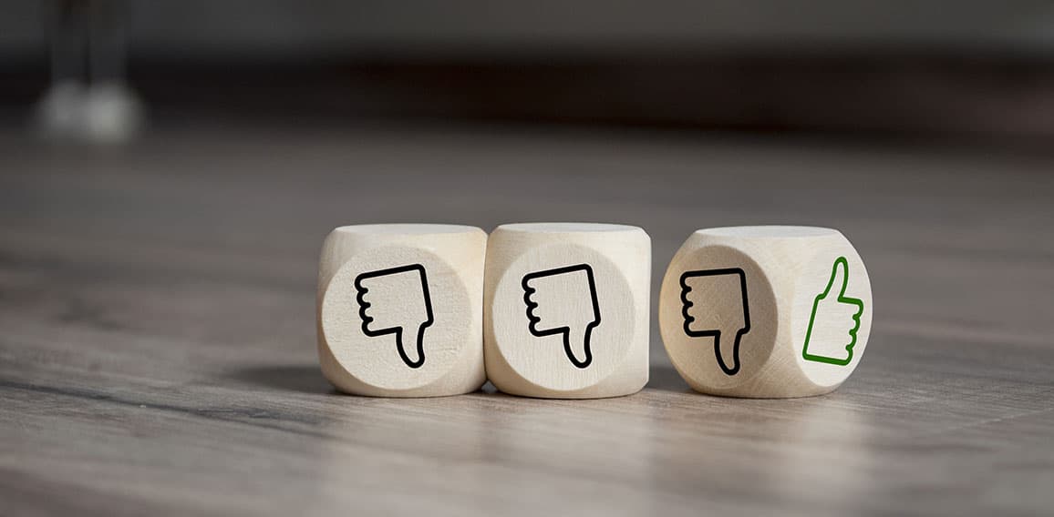 Cubes dice with thumbs up and down on wooden background