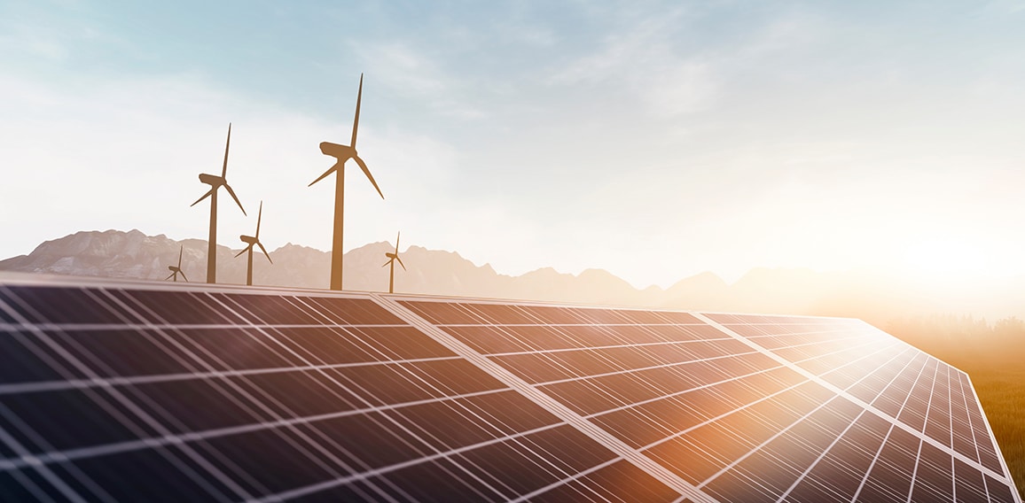 solar panels and wind power turbines in a sunset