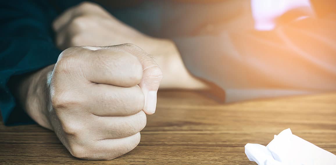 angry business man hand with crumpled paper  on table , feeling