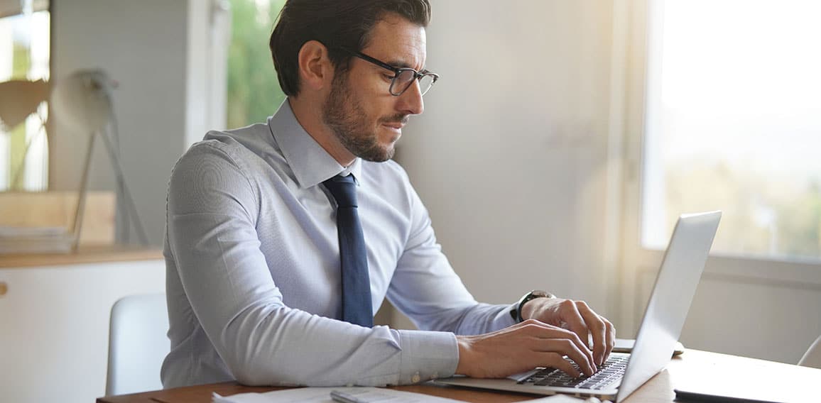 Attractive businessman typing on laptop in modern office