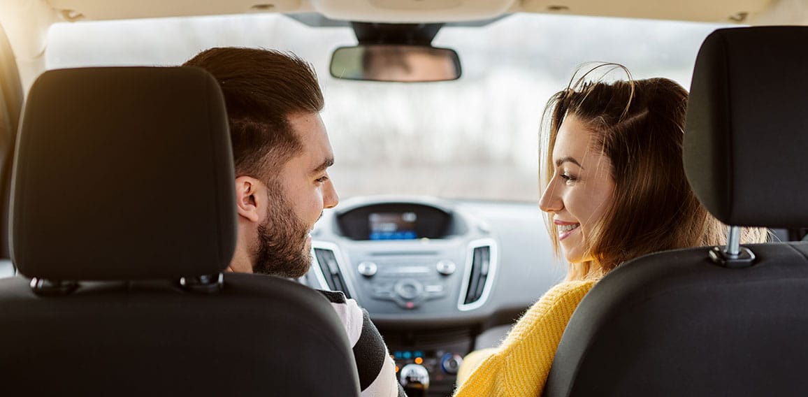 Rear view in a car of beautiful young happy love couple looking