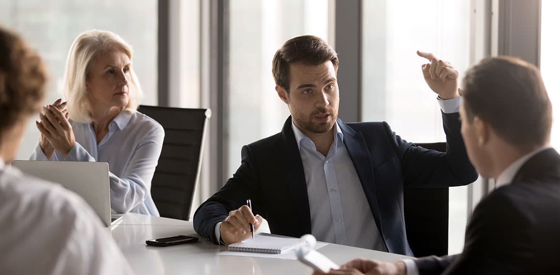 Serious businesspeople discussing new project sitting at desk in