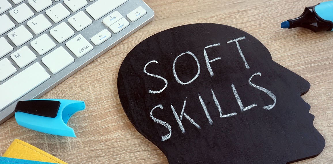 Soft skills written on a blackboard with the shape of a head.