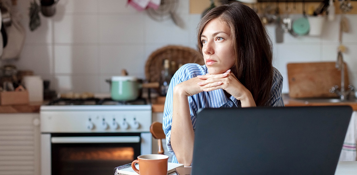 Working from home office. Upset woman using laptop and Internet. Freelancer workplace at kitchen table.