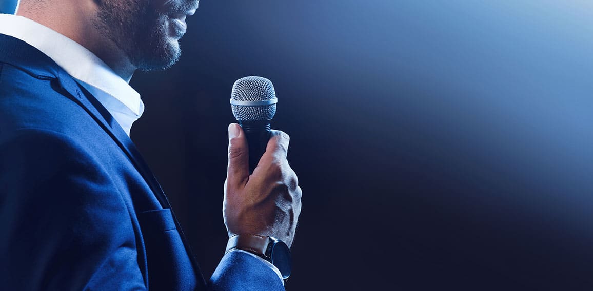 Motivational speaker with microphone performing on stage, closeu