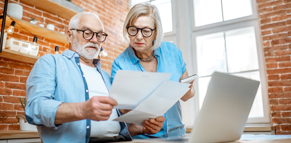 Senior couple with documents and laptop at home