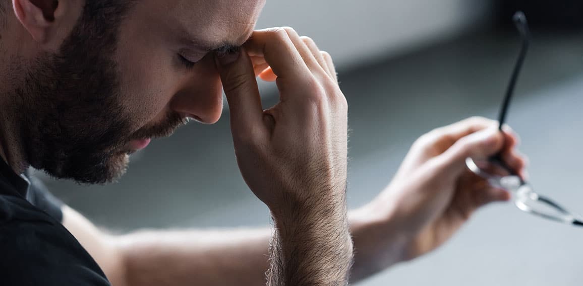 panoramic shot of depressed man with closed eyes holding glasses