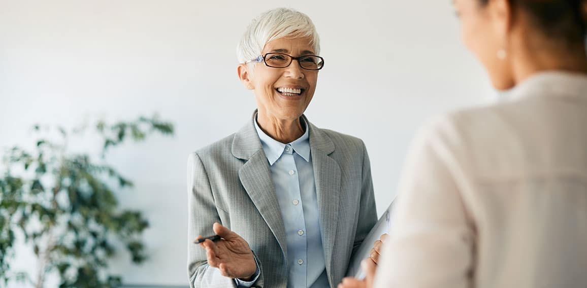 Happy mature financial consultant talks to her clients in the office.