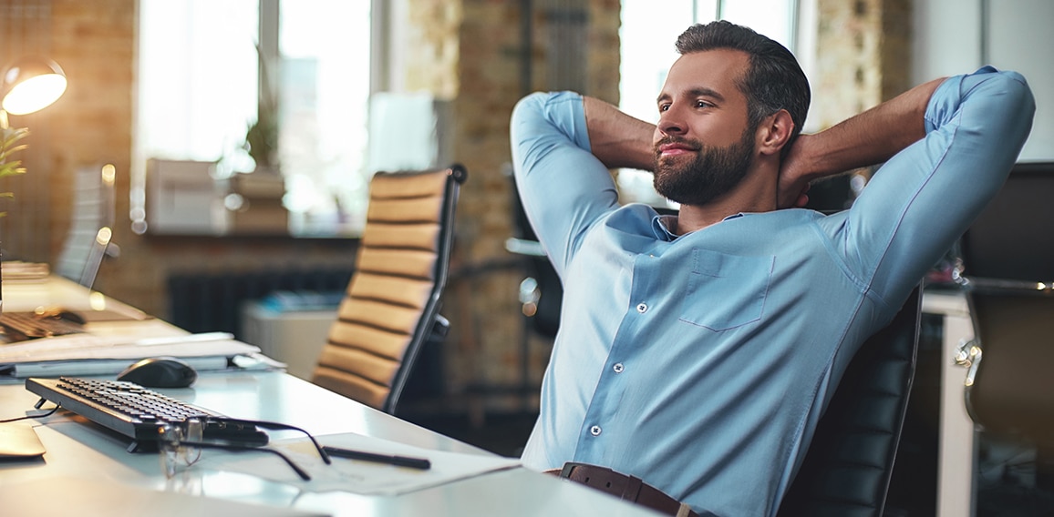 Work done. Satisfied young bearded businessman leaning back with hands behind head and relaxing while sitting in the modern office