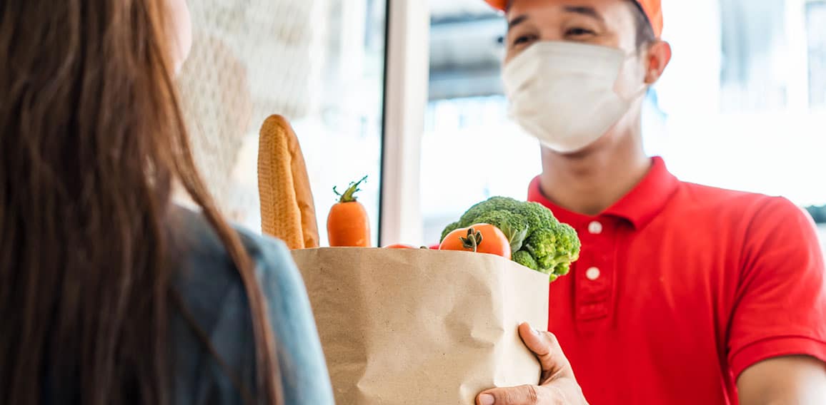 Asian deliver man wearing face mask in red uniform handling bag