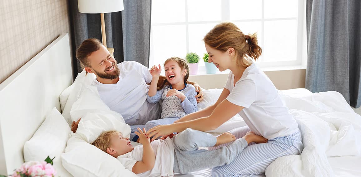 happy family mother, father and children laughing, playing and tickles in bed   at home