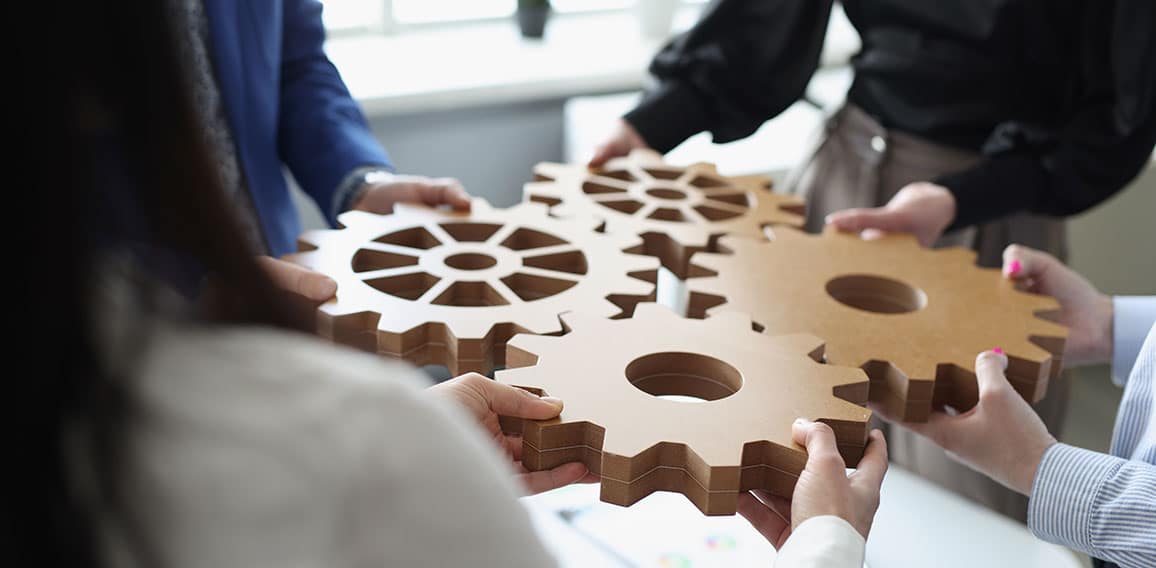 Efficient business team connects wooden gears into one