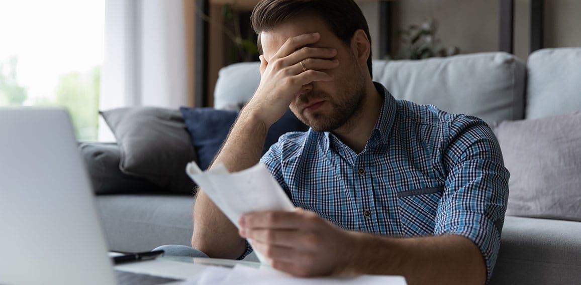 Frustrated desperate millennial man checking bills for payments