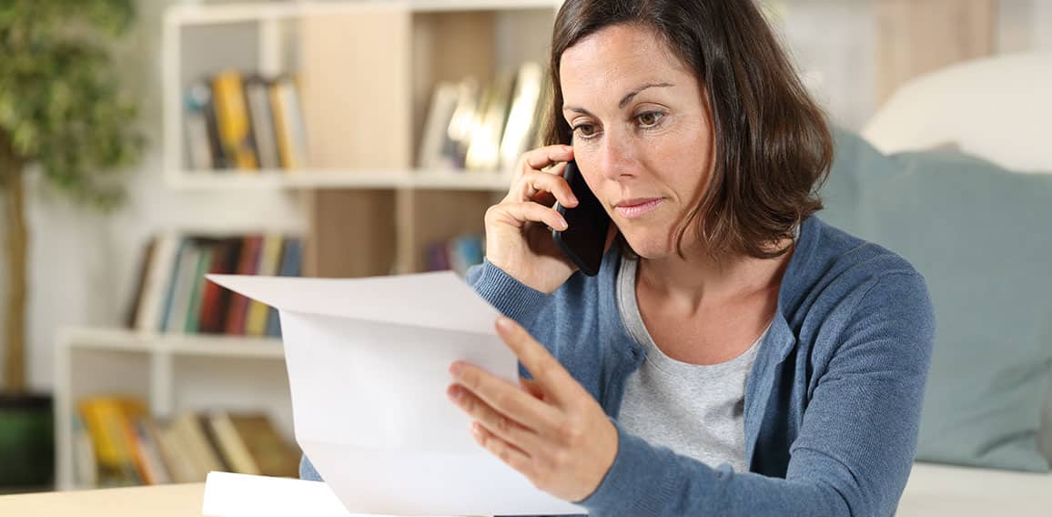 Serious adult woman checking letter calling on phone at home