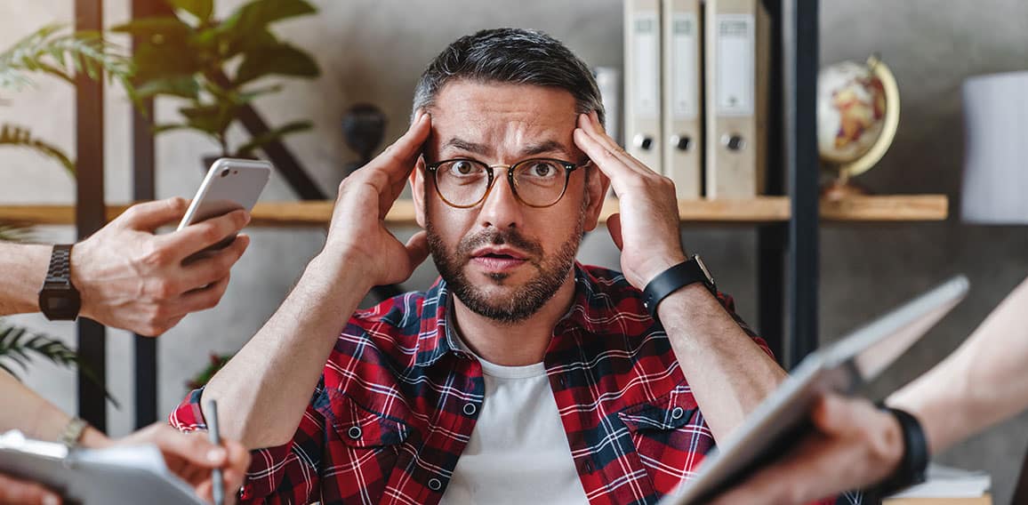 Overworked businessman sitting at laptop overloaded with work multiple tasks in modern office