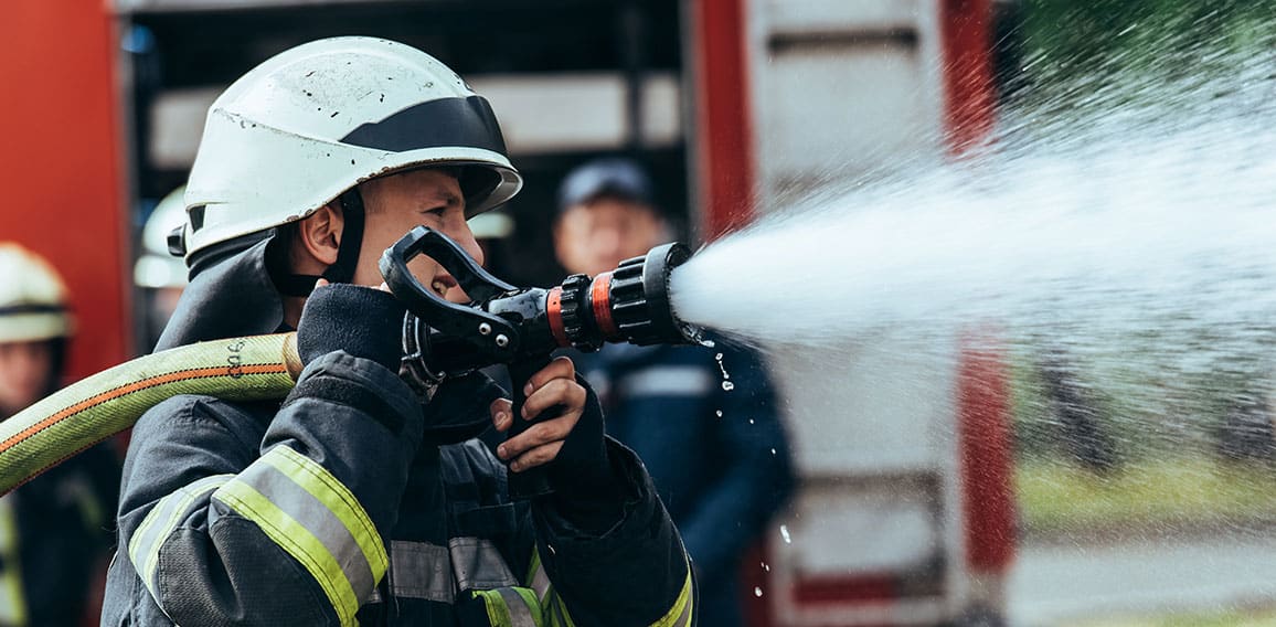 selective focus of firefighter with water hose extinguishing fir