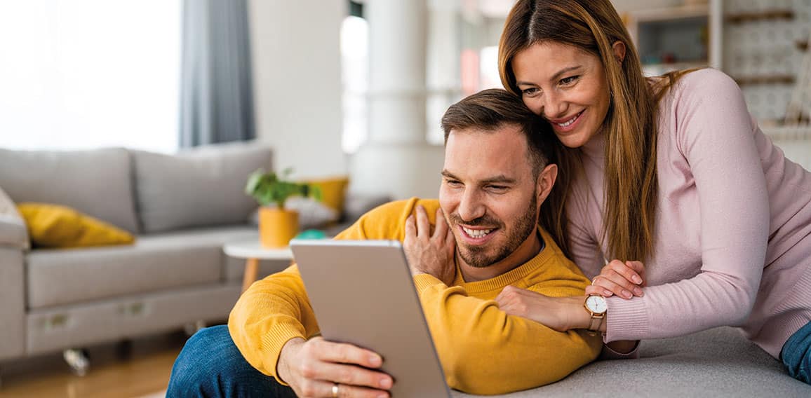 Couple in love using tablet computer at home and having fun