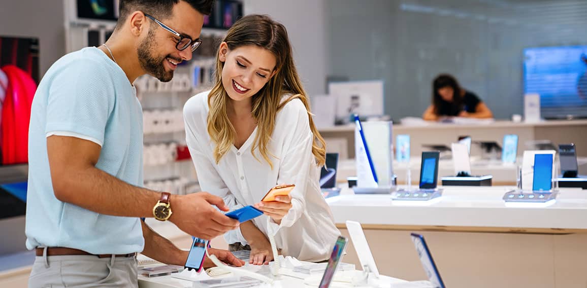 Shopping a new digital device. Happy couple buying a smartphone in store.