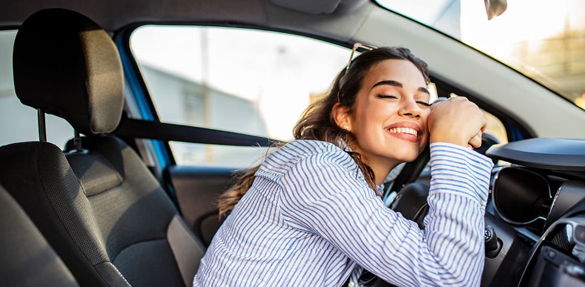 Young Woman Embracing Her New Car. Excited young woman and her n