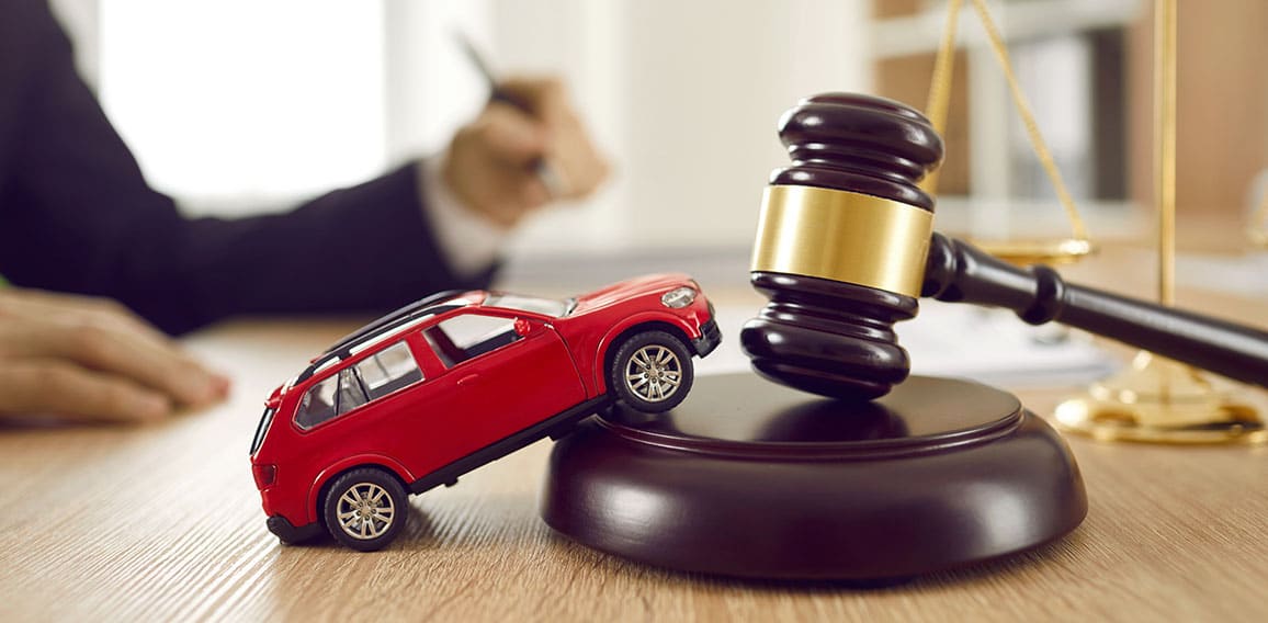 Little toy automobile on lawyer's table illustrating concept of car accident and lawsuit