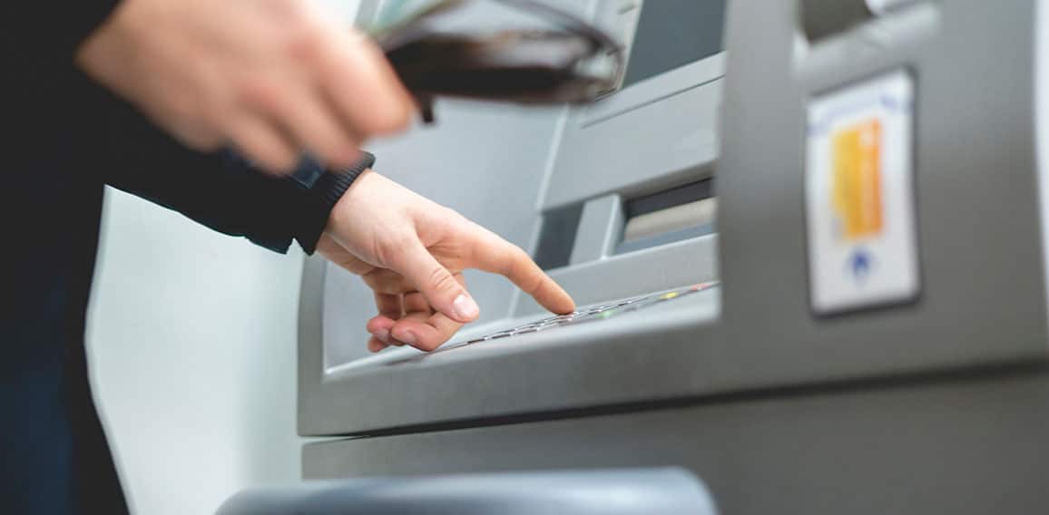 persons hand insert card in cash dispenser