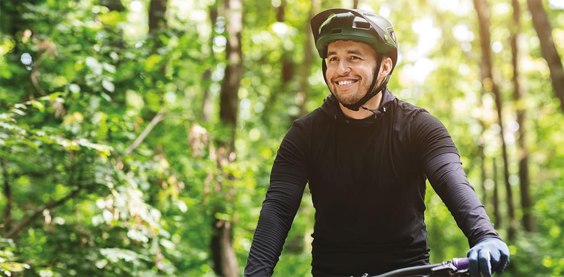 Joyful male bicyclist cycling in mountain forest